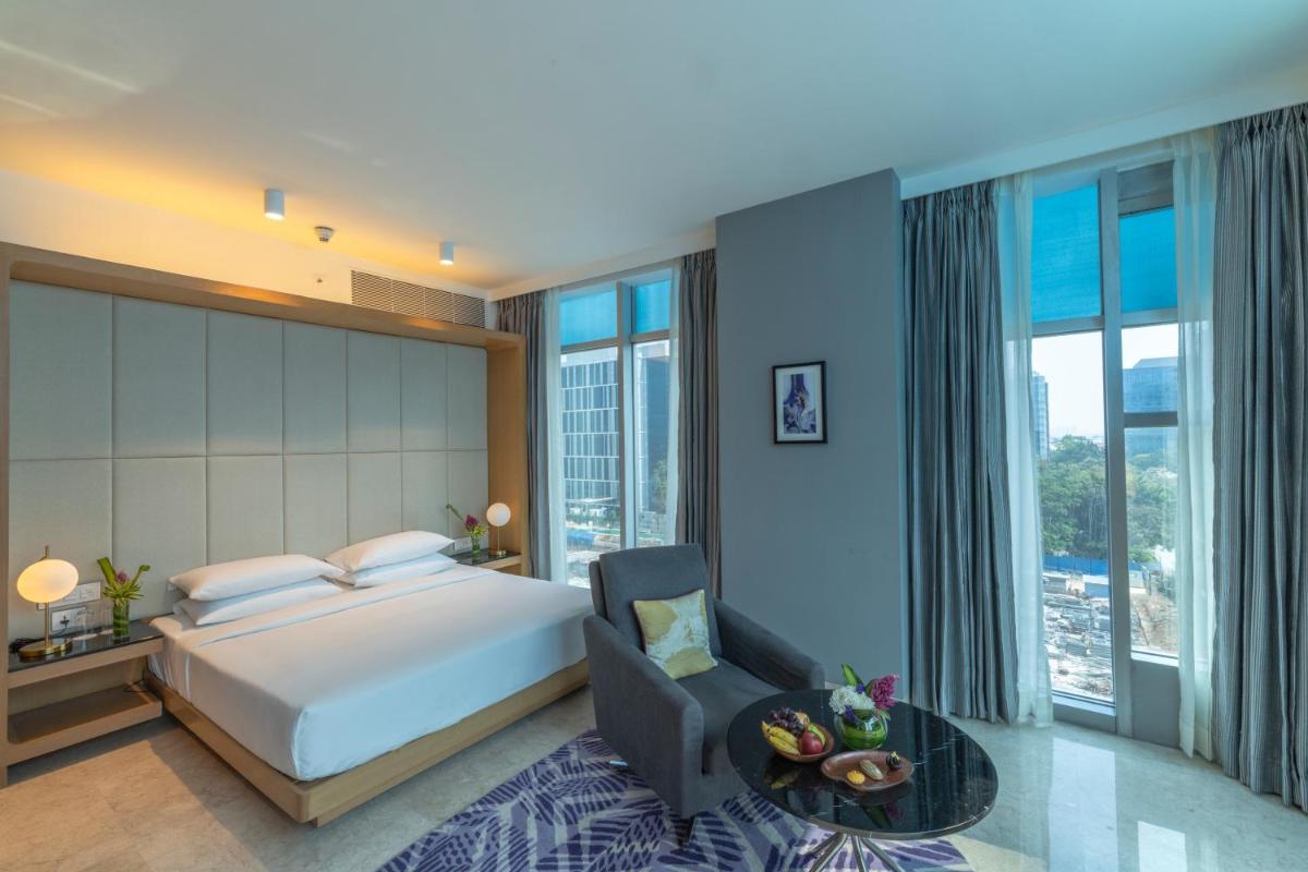 a bedroom with a king sized bed and a chair at Vivanta Bengaluru, Whitefield in Bengaluru
