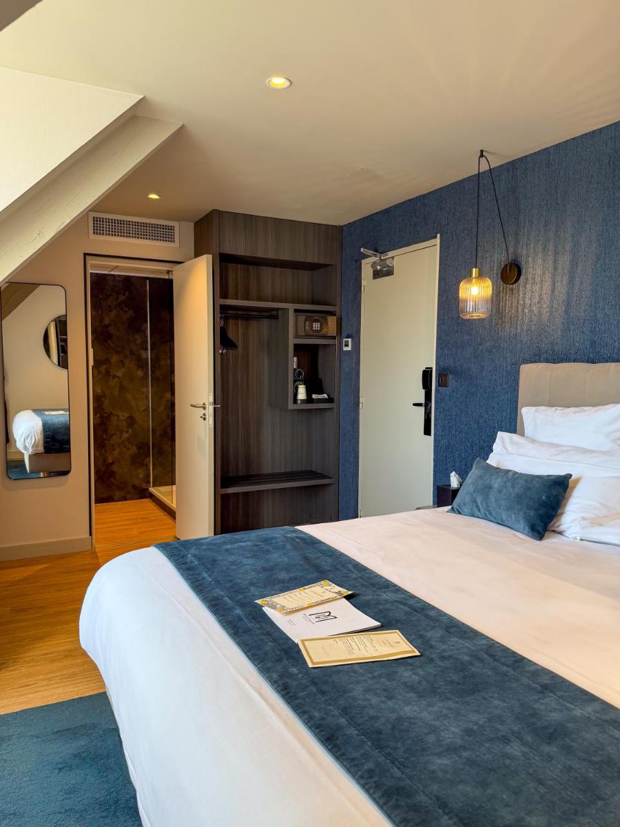 une chambre avec un grand lit avec un mur bleu dans l'établissement Hôtel & Spa Le Maury, Vannes, The Originals Boutique, à Vannes