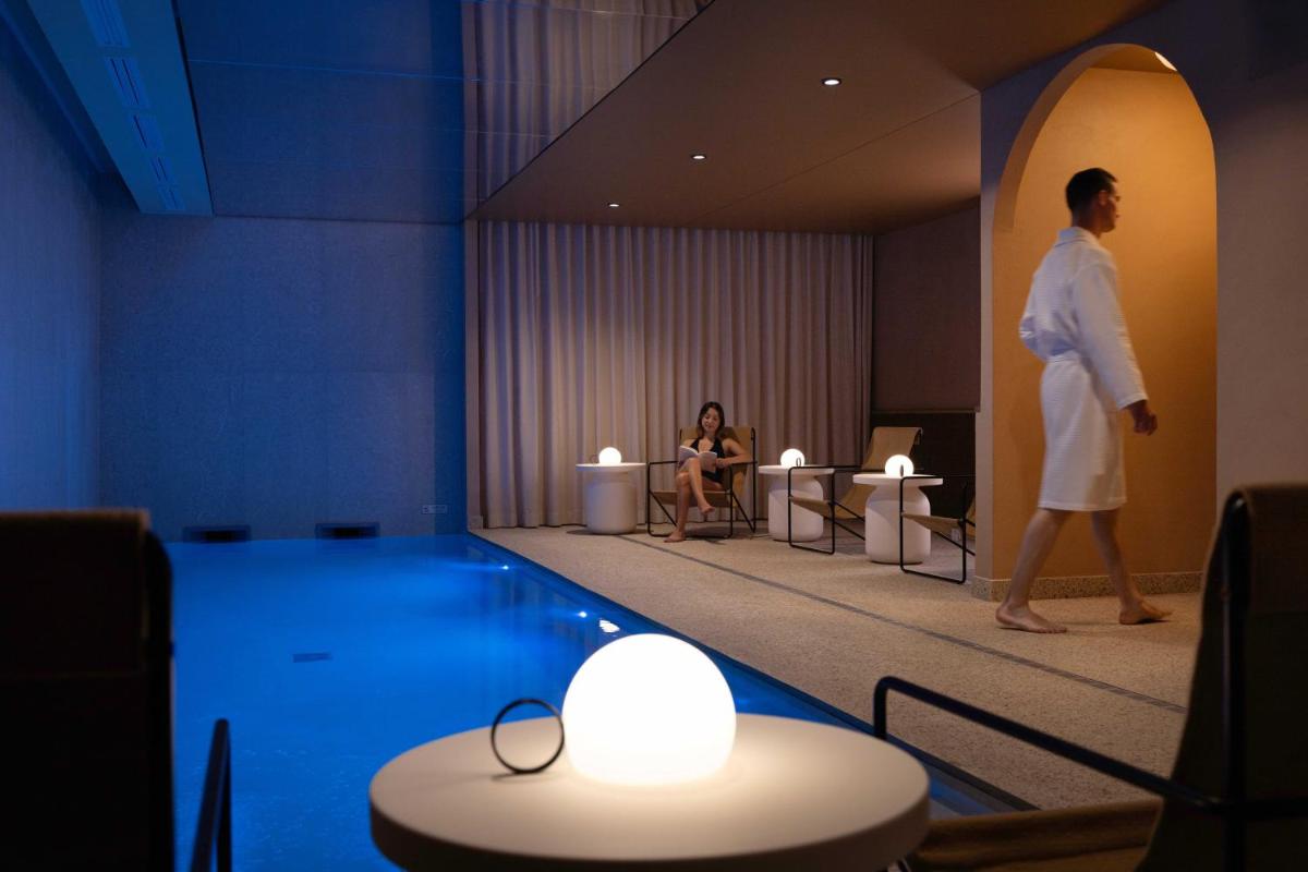 un homme marchant dans le hall d'un hôtel avec une piscine dans l'établissement Belinda Hôtel & Spa, à Paris