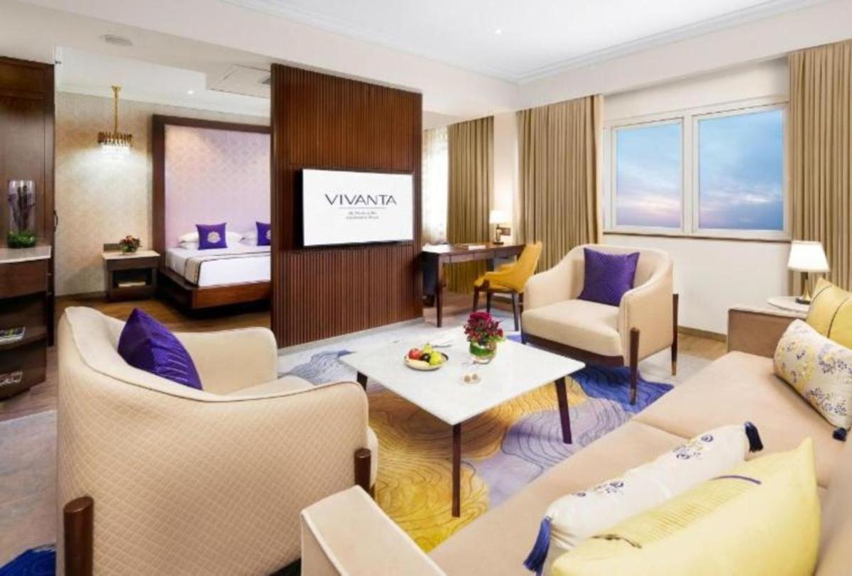 a hotel room with a couch and a bed at Vivanta Bengaluru Residency Road in Bengaluru a hotel room with a couch and a bed at Vivanta Bengaluru Residency Road in Bengaluru