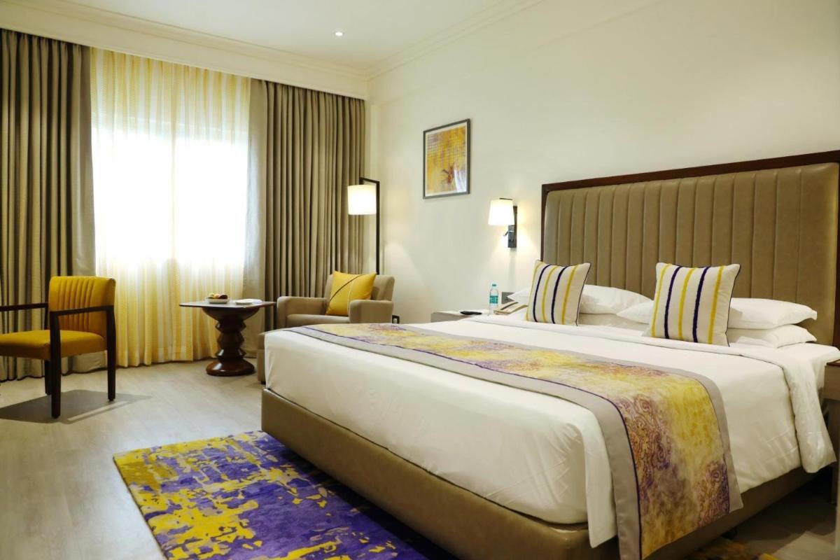 a hotel room with a large bed and a chair at Vivanta Bengaluru Residency Road in Bengaluru a hotel room with a large bed and a chair at Vivanta Bengaluru Residency Road in Bengaluru