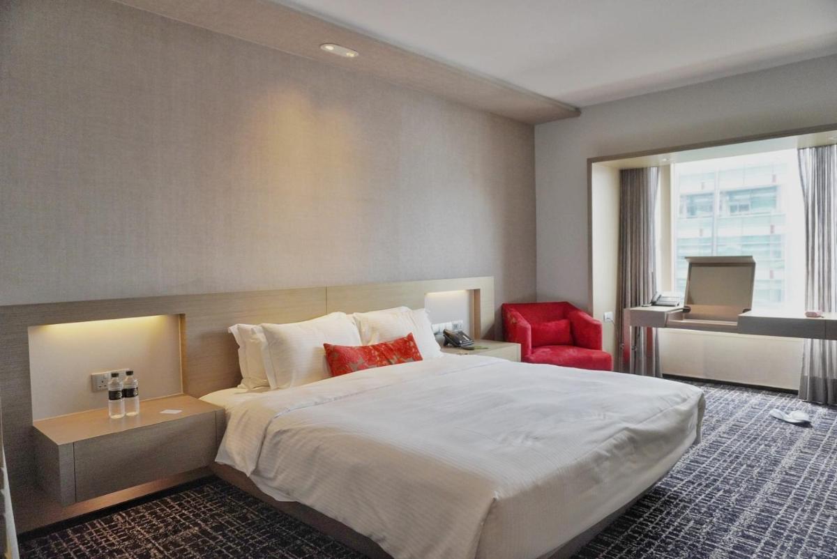 a hotel room with a large bed and a red chair at Carlton Hotel Singapore in Singapore a hotel room with a large bed and a red chair at Carlton Hotel Singapore in Singapore