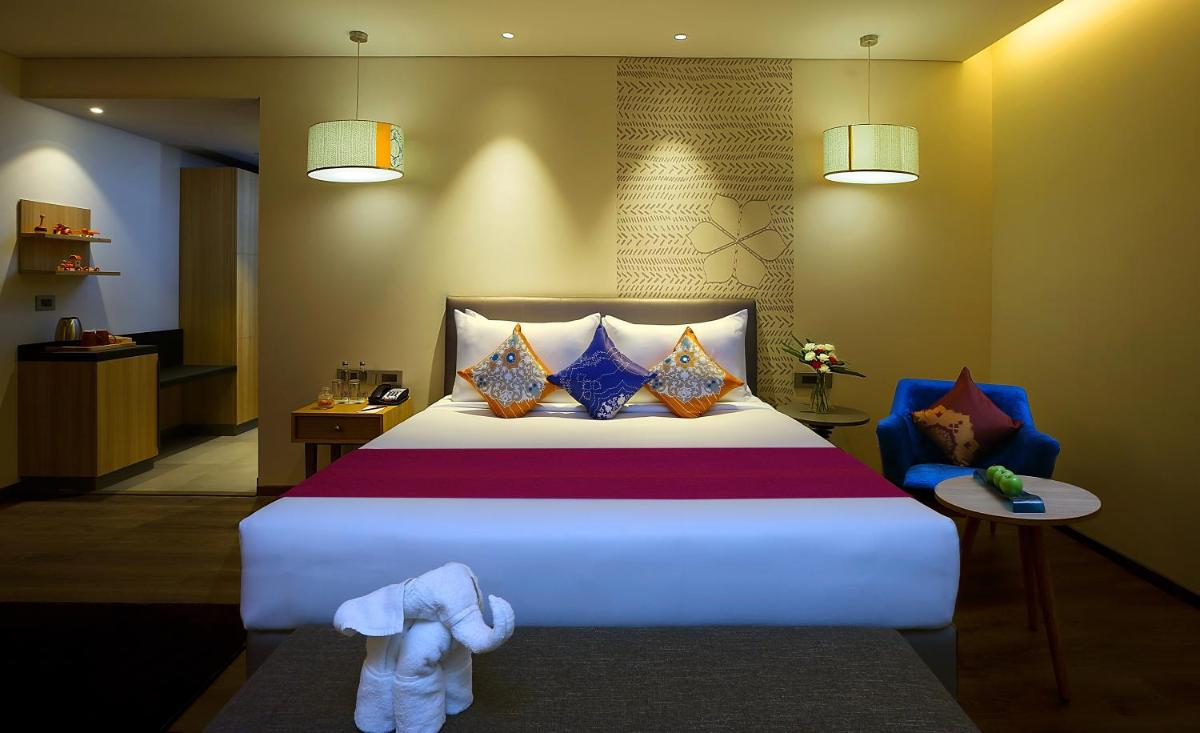 a bedroom with a large bed and a blue chair at Grand Mercure Mysore - An Accor Brand in Mysore