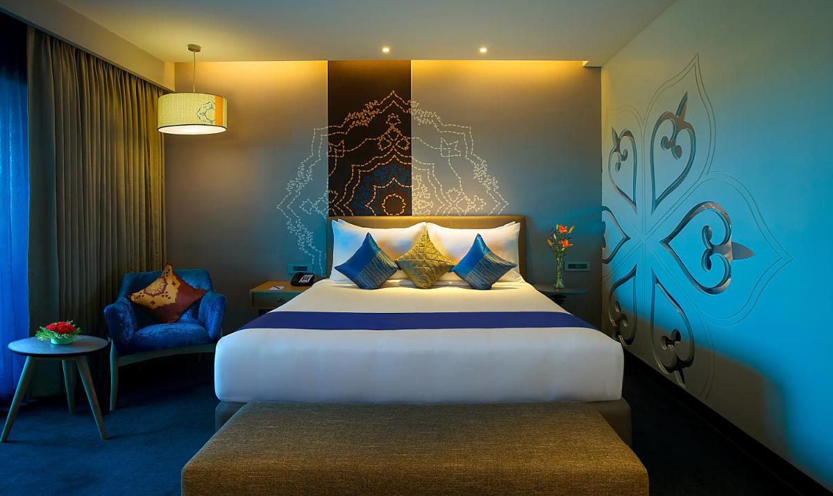 a hotel room with a bed and a chair at Grand Mercure Mysore - An Accor Brand in Mysore