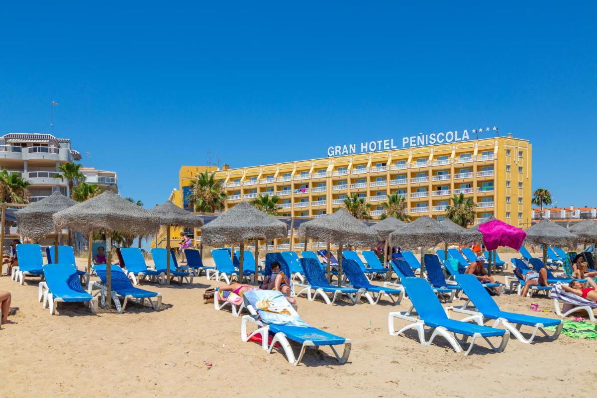 Un grupo de sillas y sombrillas en una playa. en Gran Hotel Peñiscola, en Peñíscola