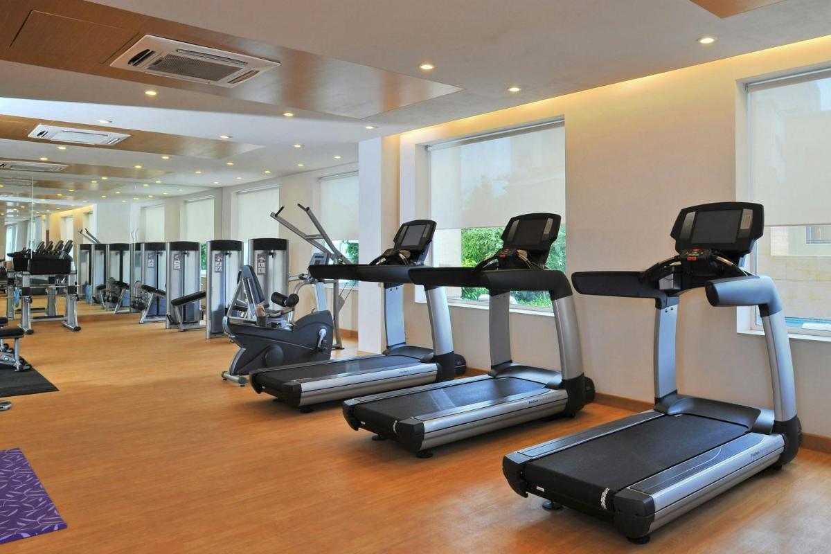 a gym with a row of tread machines in a room at Four Points by Sheraton Hotel and Serviced Apartments Pune in Pune