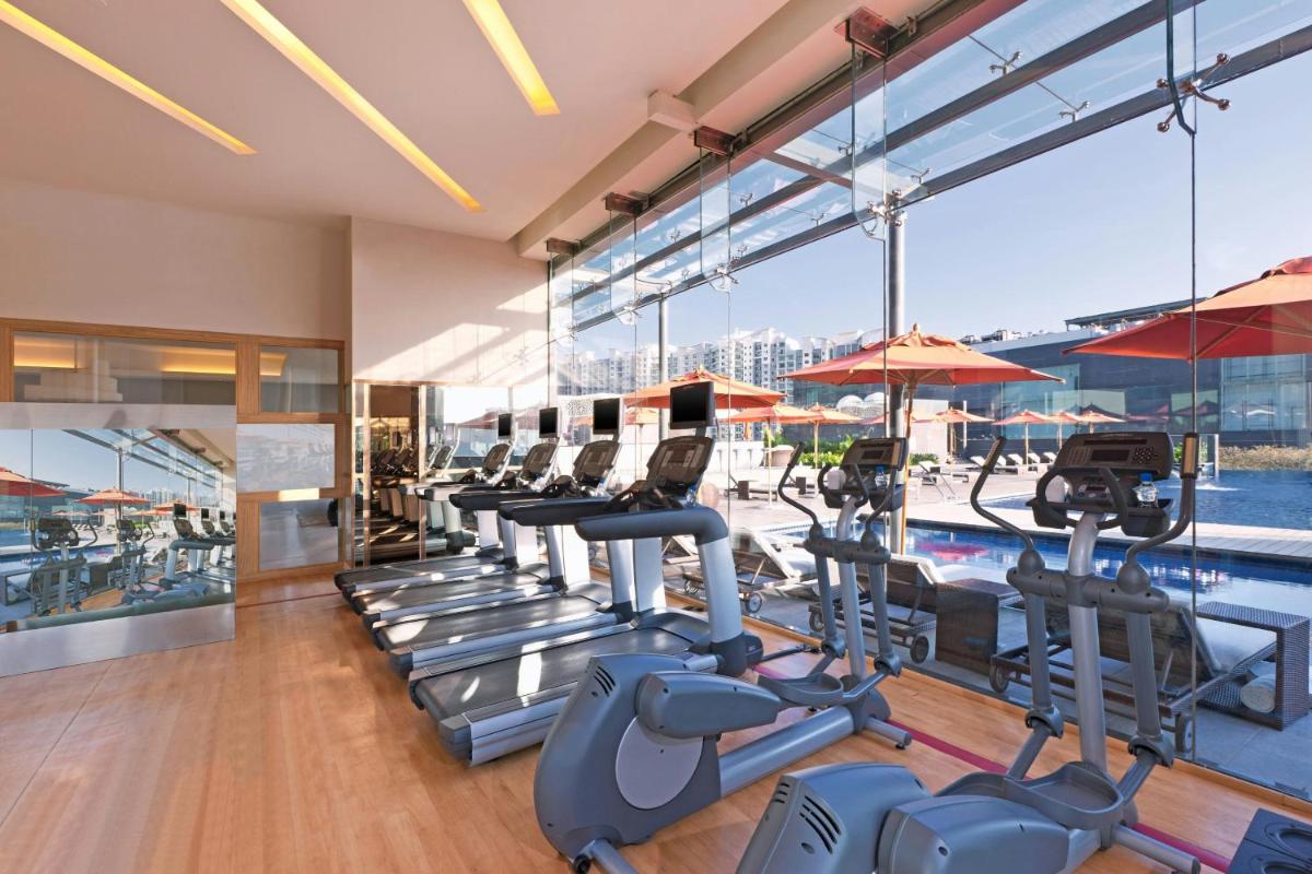 a gym with a row of treadmills and a pool at Sheraton Grand Bangalore Hotel at Brigade Gateway in Bengaluru