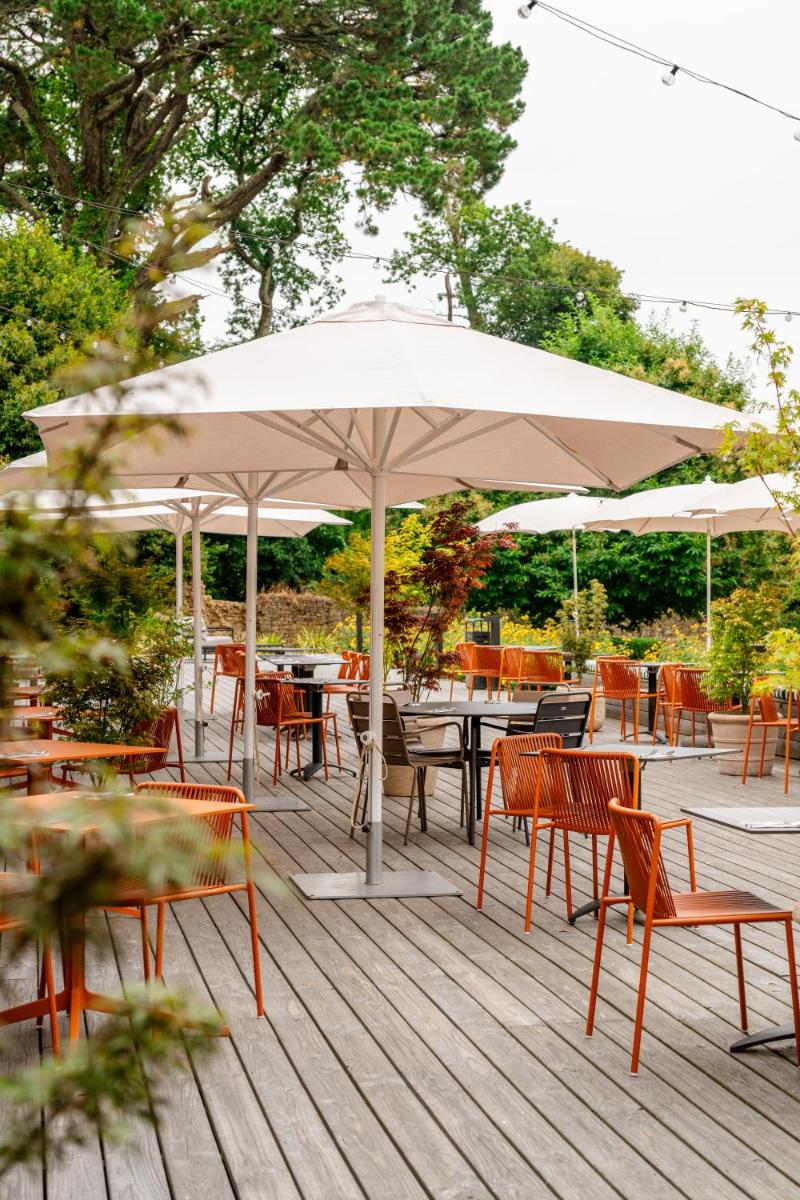 un patio avec tables, chaises et un parasol dans l'établissement La Maison OBONO Hôtel & Spa, au Bono