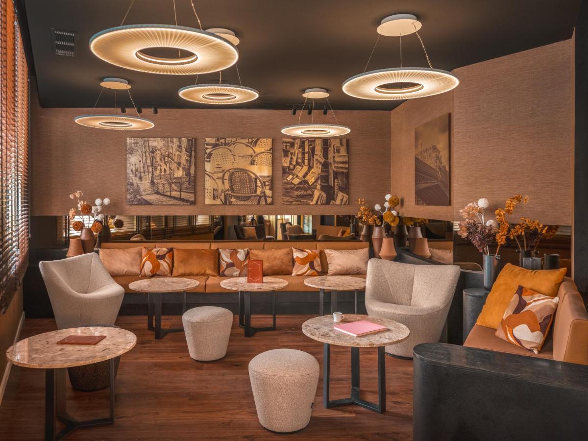 - un hall avec un canapé, des tables et des chaises dans l'établissement Hôtel Barnett Paris, à Paris