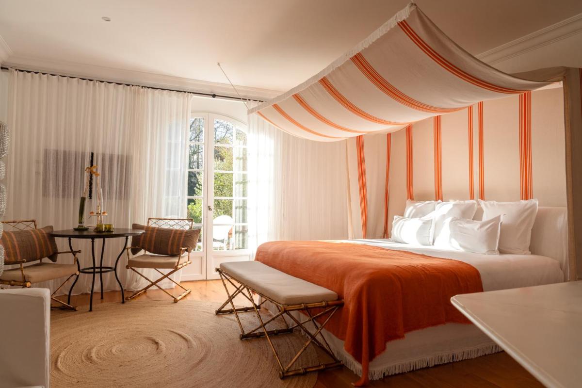 une chambre avec un lit recouvert d'une couverture orange et une table dans l'établissement Brindos, Lac & Château - Relais & Châteaux - Anglet Biarritz, à Anglet
