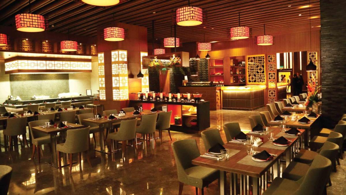 a restaurant with tables and chairs and a bar at Holiday Inn New Delhi Mayur Vihar Noida by IHG in New Delhi a restaurant with tables and chairs and a bar at Holiday Inn New Delhi Mayur Vihar Noida by IHG in New Delhi