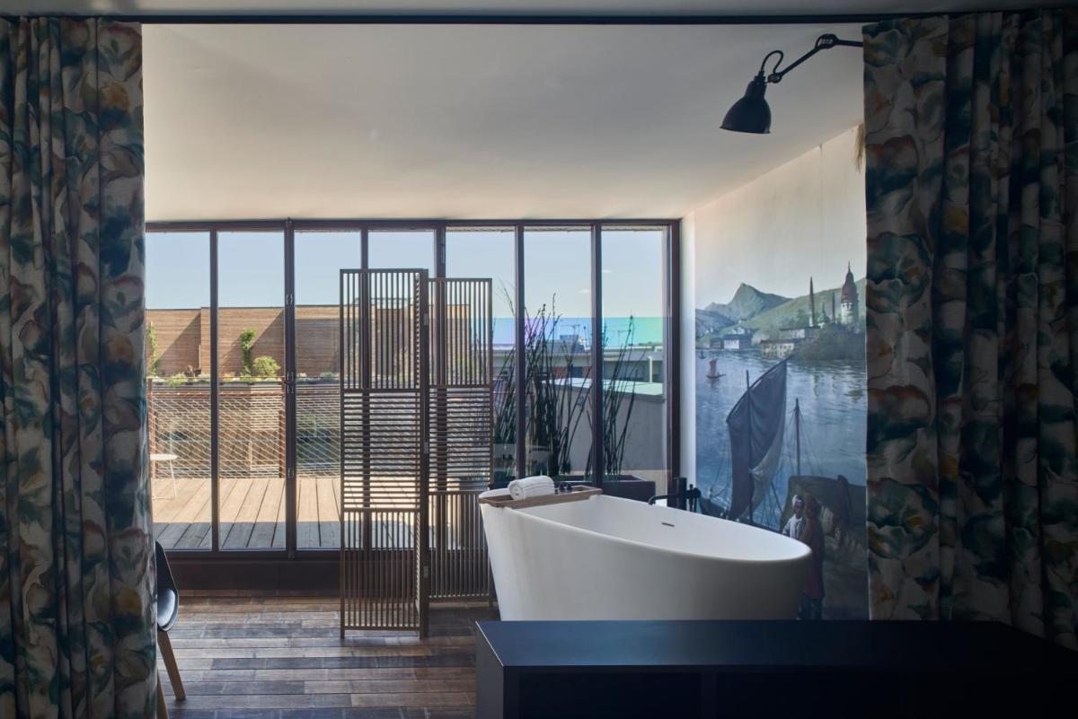 une salle de bain avec baignoire et une grande fenêtre dans l'établissement Hotel La Zoologie & Spa Bordeaux, à Bordeaux