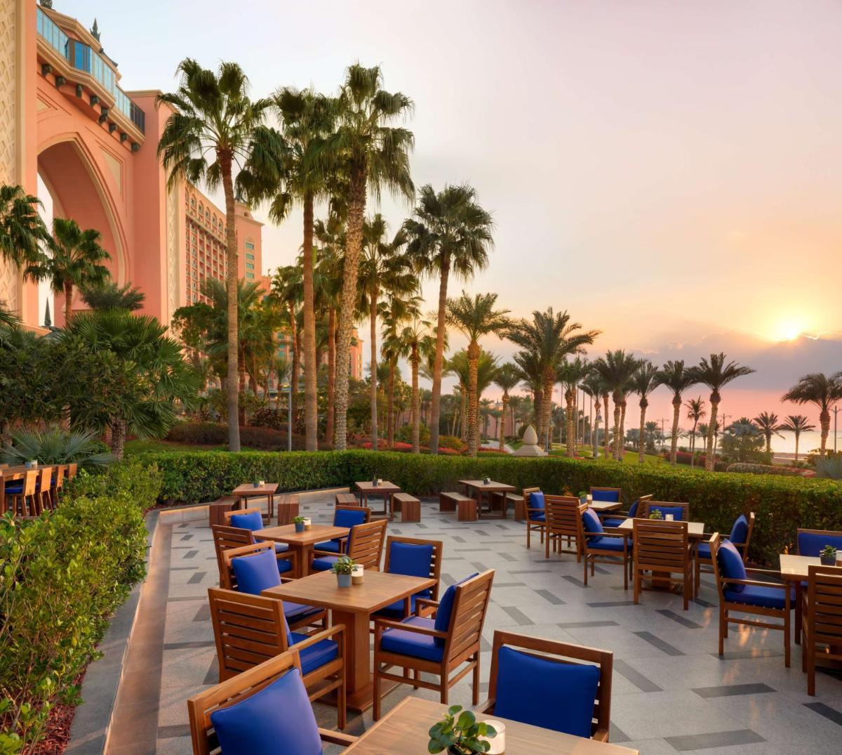 a patio at the resort with tables and chairs and palm trees at Atlantis, The Palm in Dubai