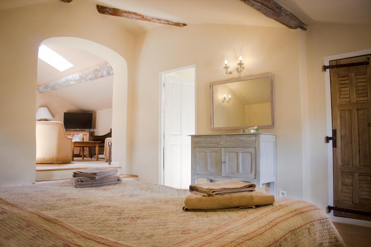 une chambre avec un grand lit et un miroir dans l'établissement Les Carmes and spa, au Thor