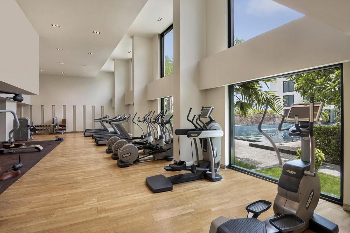 a gym with a row of treadmills and ellipticals at Pullman New Delhi Aerocity in New Delhi a gym with a row of treadmills and ellipticals at Pullman New Delhi Aerocity in New Delhi