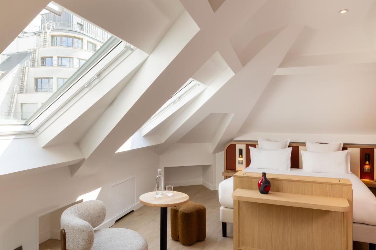 - une chambre en mezzanine avec un lit et des chaises dans l'établissement Madame Drouot & Spa - Opera, à Paris