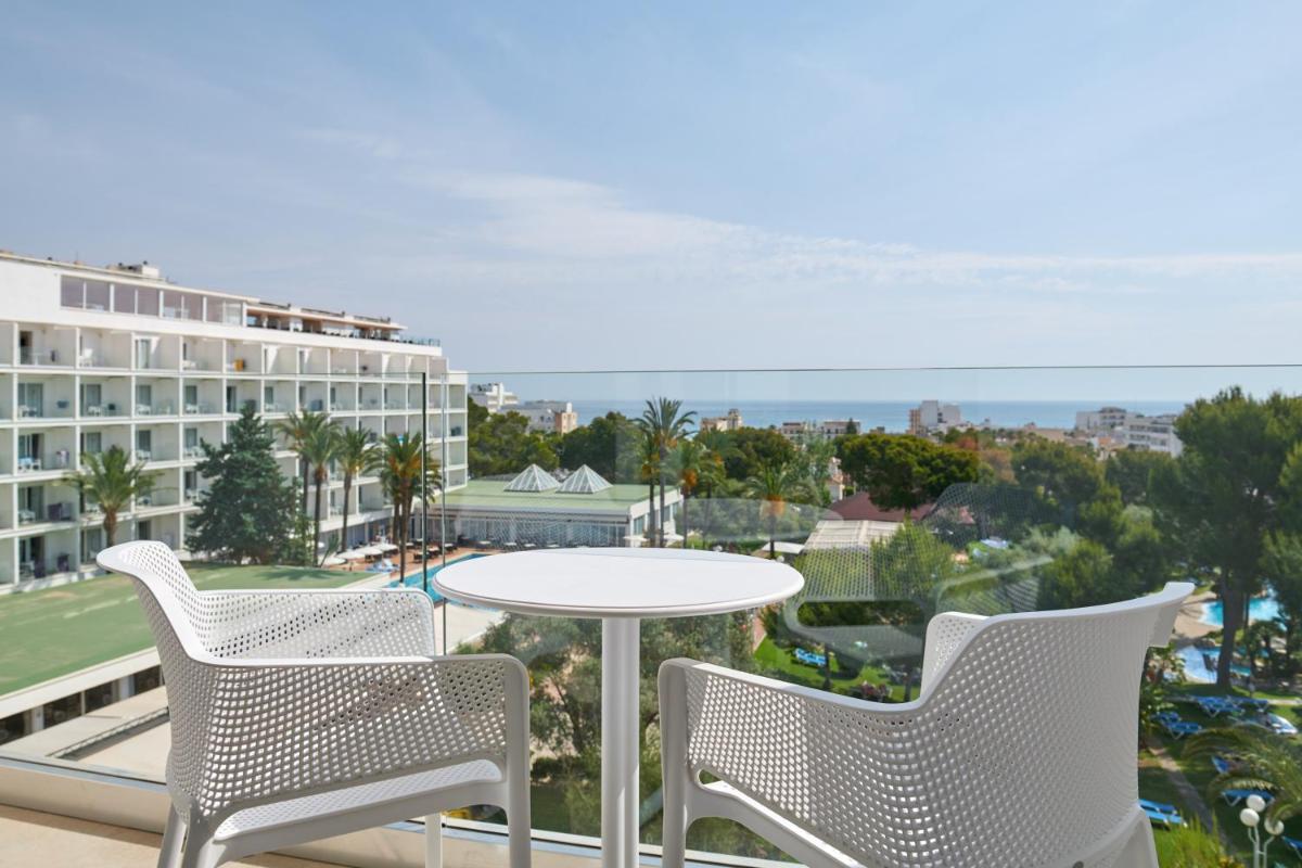 Un balcón con una mesa y sillas y un edificio. en Grupotel Gran Vista & Spa, en Can Picafort