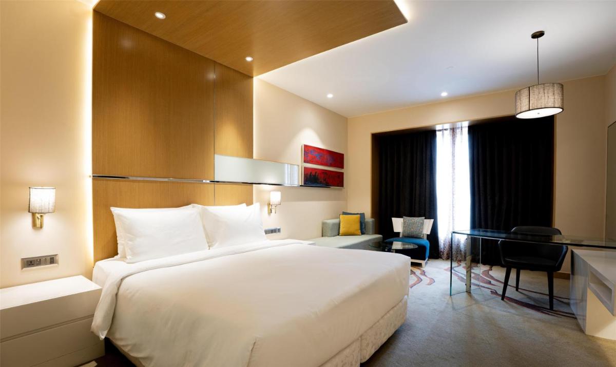 a bedroom with a large white bed and a desk at Radisson Blu Hotel Amritsar in Amritsar