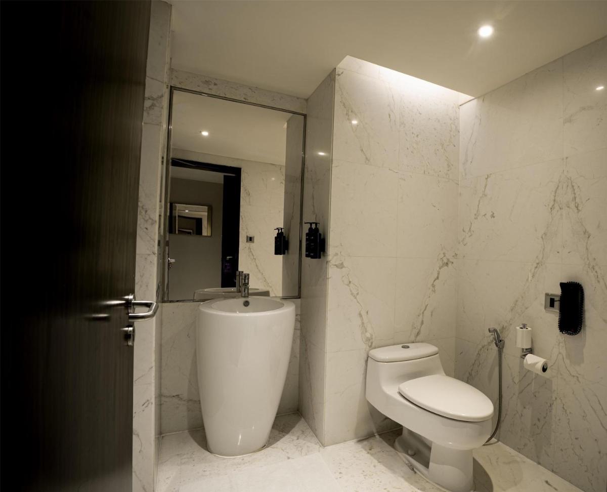 a white bathroom with a toilet and a sink at Radisson Blu Hotel Amritsar in Amritsar