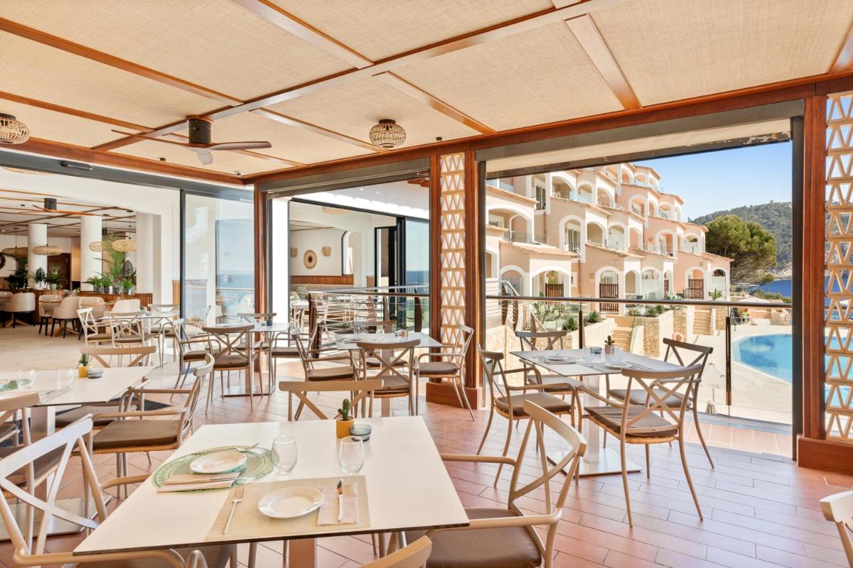 un restaurante con mesas y sillas y vistas a un edificio en Bahia Suites Camp de Mar, en Camp de Mar