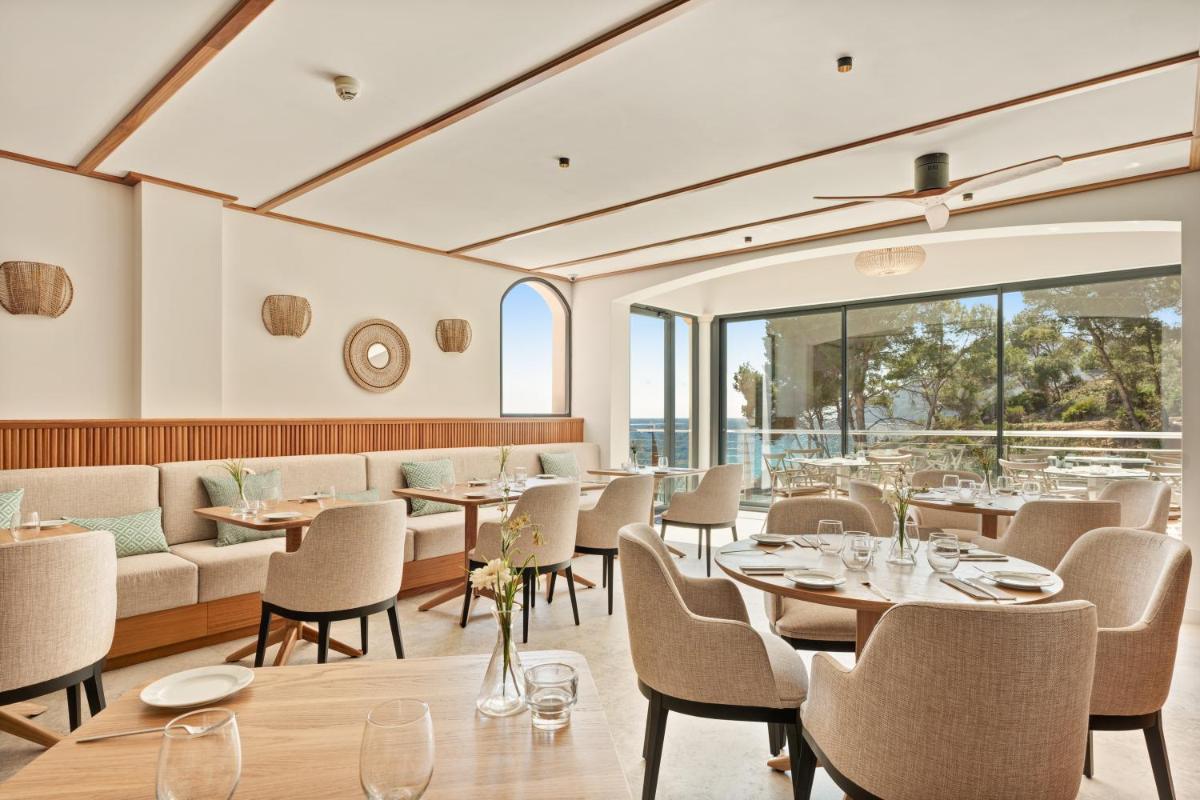 Un comedor con mesas y sillas y ventanas. en Bahia Suites Camp de Mar, en Camp de Mar