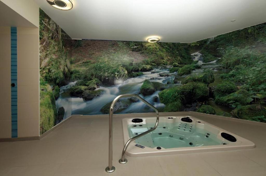 une salle de bains ornée d'un tableau représentant une rivière dans l'établissement Logis Hôtel Restaurant Auberge de la Xaintrie, à Saint-Privat