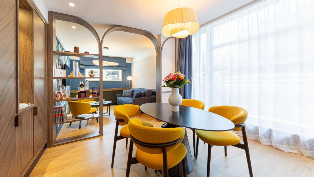 un salon avec une table et des chaises jaunes dans l'établissement Le Riviera - Hôtel Restaurant & Spa - Ex Golden Tulip Aix les bains, à Aix-les-Bains