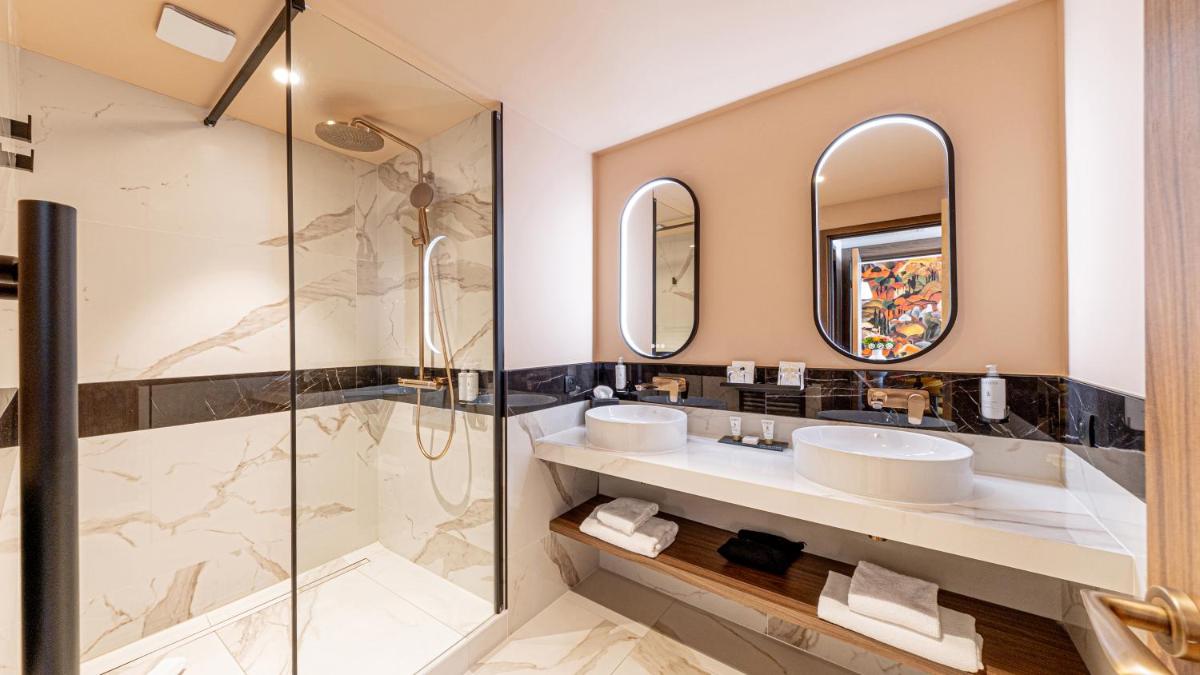 une salle de bain avec deux lavabos et une douche dans l'établissement Le Riviera - Hôtel Restaurant & Spa - Ex Golden Tulip Aix les bains, à Aix-les-Bains