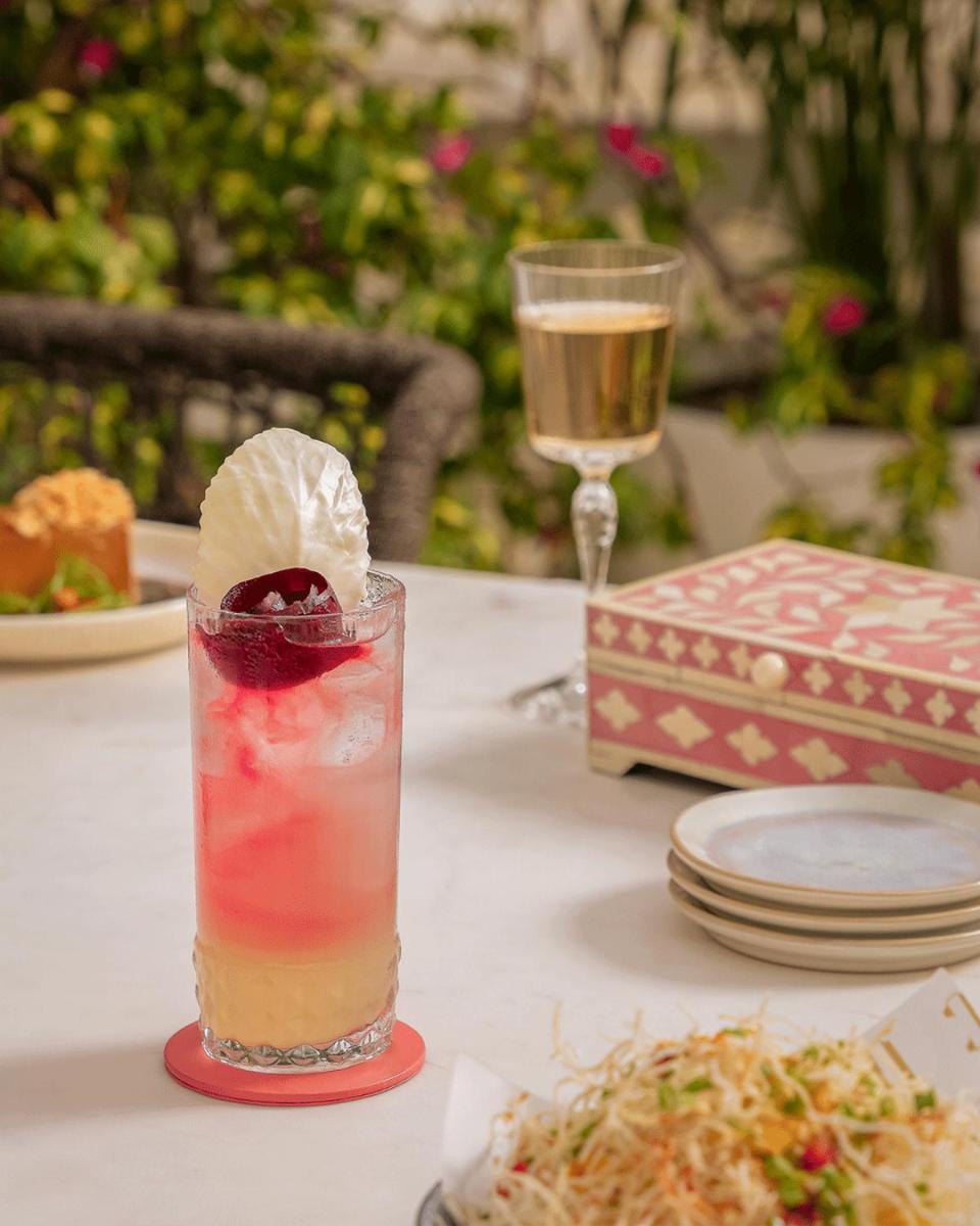 a drink on a table with plates and a wine glass at Hyatt Regency Jaipur Mansarovar in Jaipur a drink on a table with plates and a wine glass at Hyatt Regency Jaipur Mansarovar in Jaipur