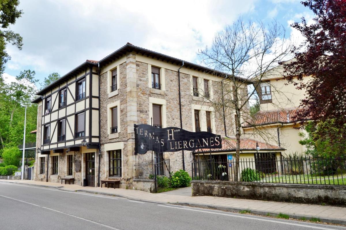 Un gran edificio de ladrillo al costado de una calle. en Hotel Termas de Liérganes, en Liérganes