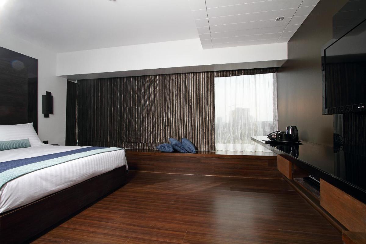 a bedroom with a bed and a large window at Svenska Design Hotel in Mumbai