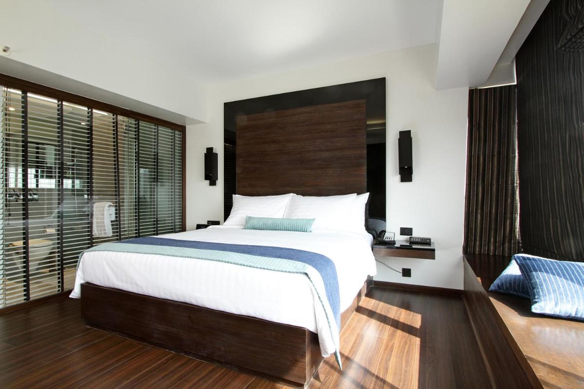 a bedroom with a large bed and a large window at Svenska Design Hotel in Mumbai