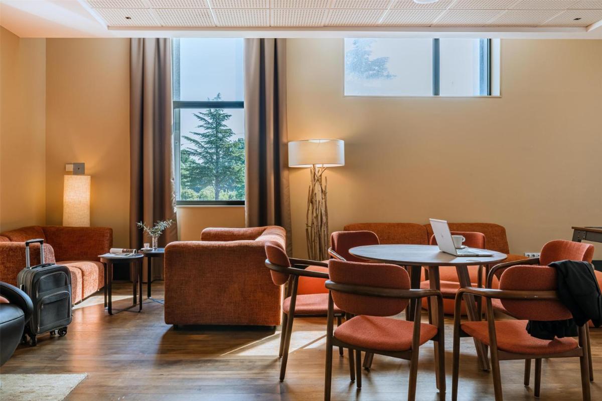 une salle d'attente avec une table et des chaises dans l'établissement DoubleTree by Hilton Lyon Eurexpo & Spa, à Saint-Priest 42 autres photos