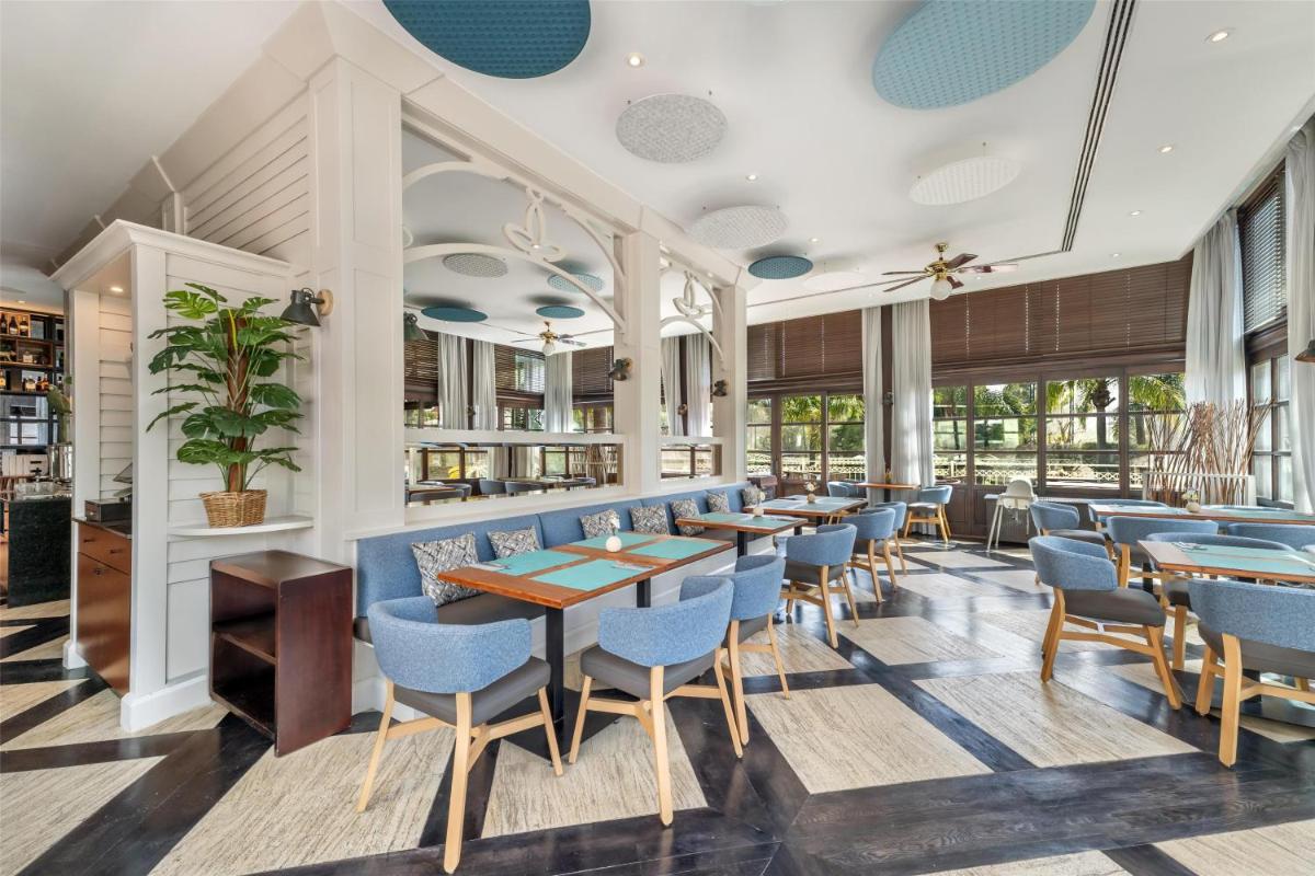 un restaurante con sillas azules, mesas y ventanas en Lindner Hotel Mallorca Portals Nous, part of JdV by Hyatt, en Portals Nous