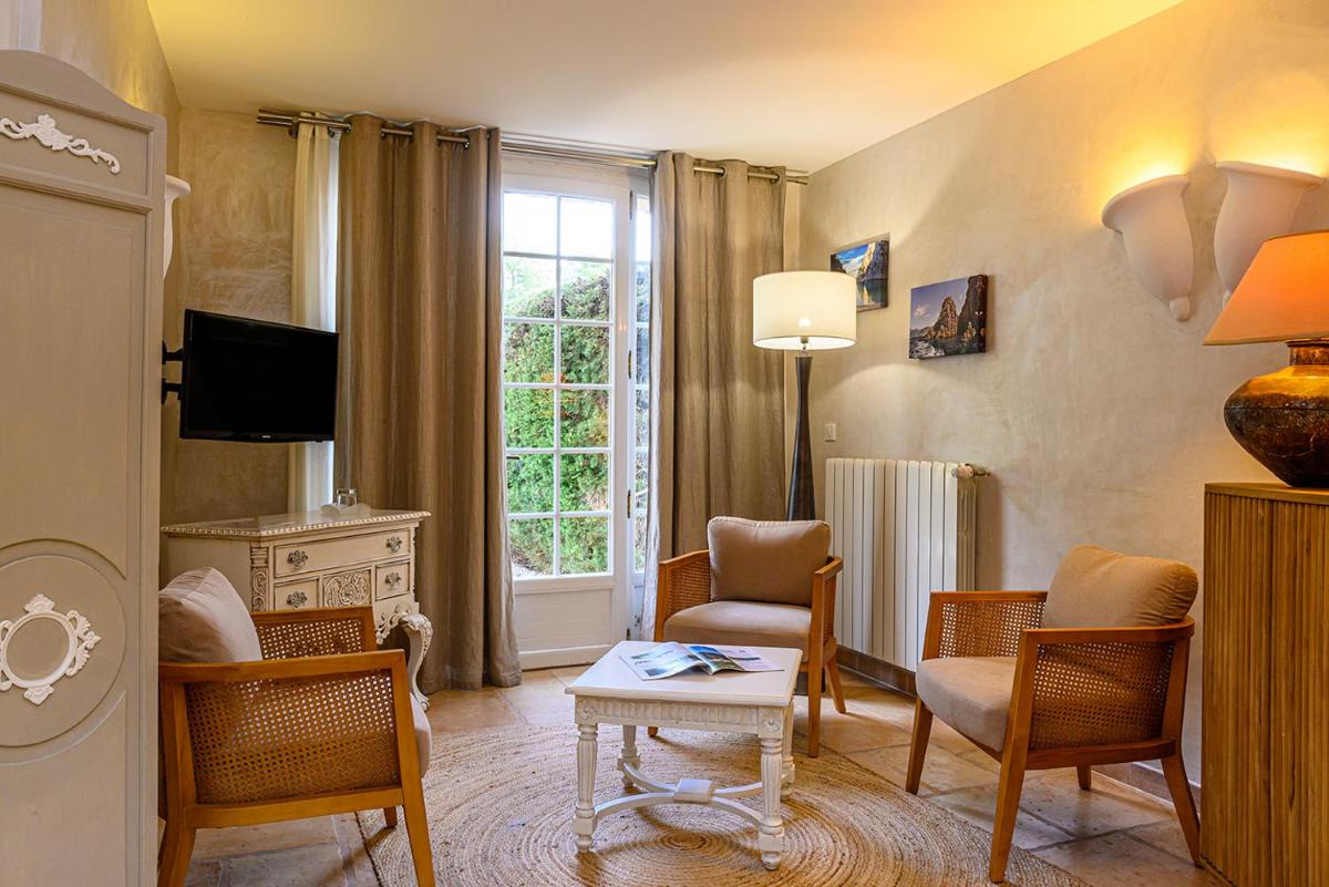 un salon avec des chaises, une table et une télévision dans l'établissement La Bastide De Tourtour Hotel & Spa, à Tourtour