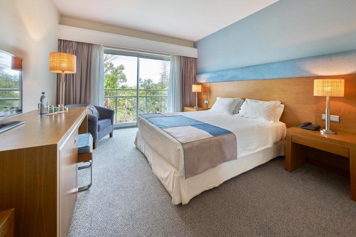 um quarto de hotel com uma cama grande e uma casa de banho em Hotel Do Caracol em Angra do Heroísmo