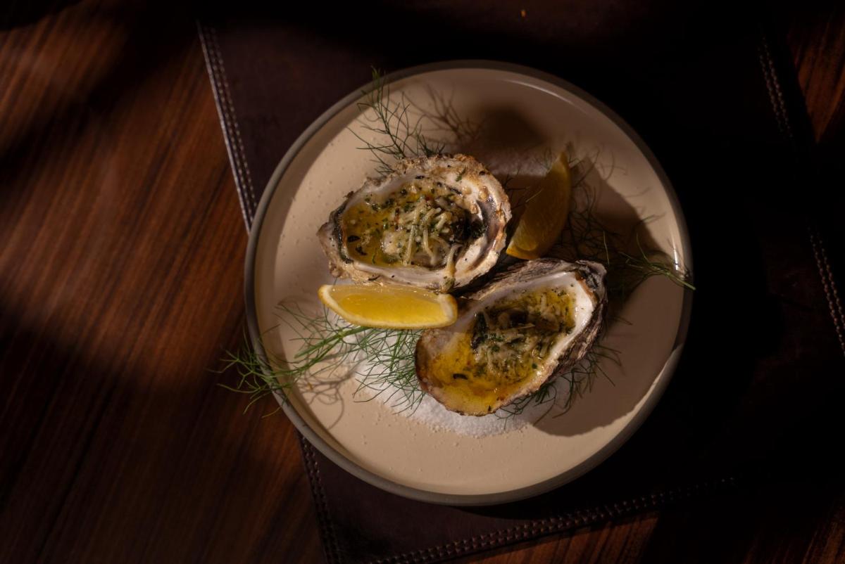 a plate of food with oysters and lemon on a table at Four Seasons Hotel Bengaluru at Embassy ONE in Bengaluru a plate of food with oysters and lemon on a table at Four Seasons Hotel Bengaluru at Embassy ONE in Bengaluru