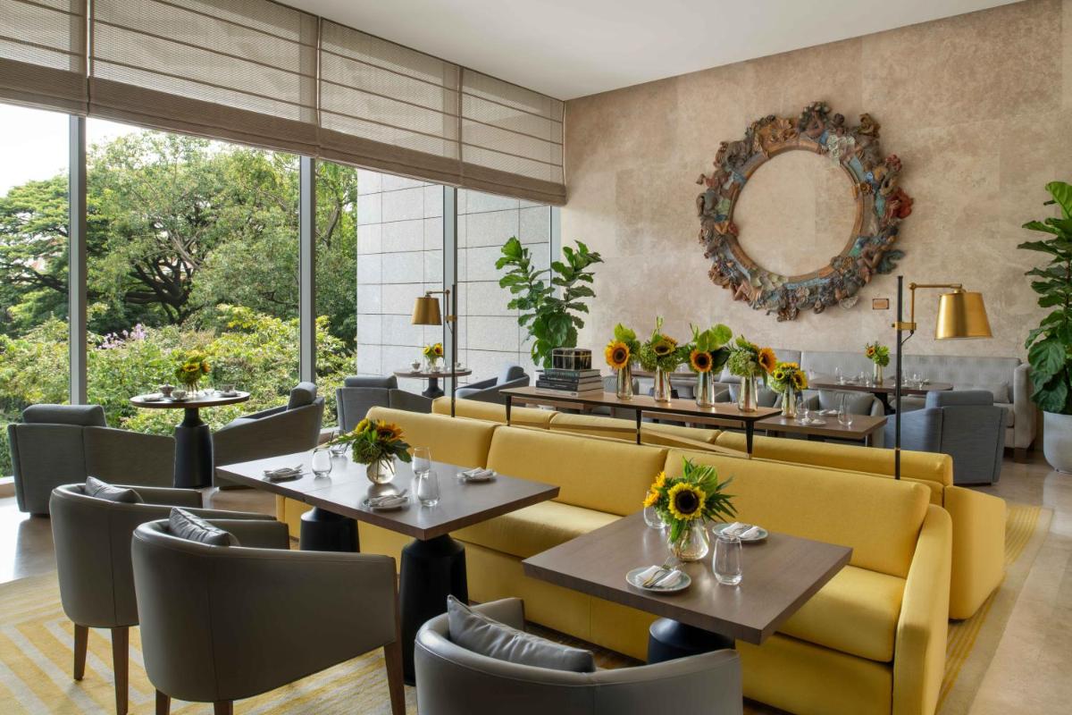 a restaurant with yellow chairs and tables and a mirror at Four Seasons Hotel Bengaluru at Embassy ONE in Bengaluru a restaurant with yellow chairs and tables and a mirror at Four Seasons Hotel Bengaluru at Embassy ONE in Bengaluru