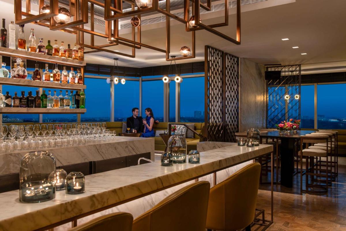 a restaurant with a long bar with people in the background at Four Seasons Hotel Bengaluru at Embassy ONE in Bengaluru a restaurant with a long bar with people in the background at Four Seasons Hotel Bengaluru at Embassy ONE in Bengaluru