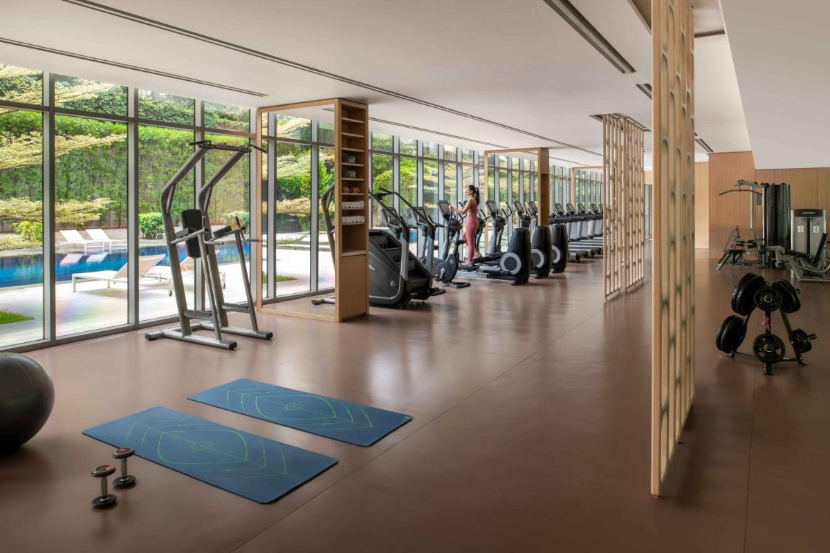 a gym with pilates equipment and a swimming pool at Four Seasons Hotel Bengaluru at Embassy ONE in Bengaluru a gym with pilates equipment and a swimming pool at Four Seasons Hotel Bengaluru at Embassy ONE in Bengaluru