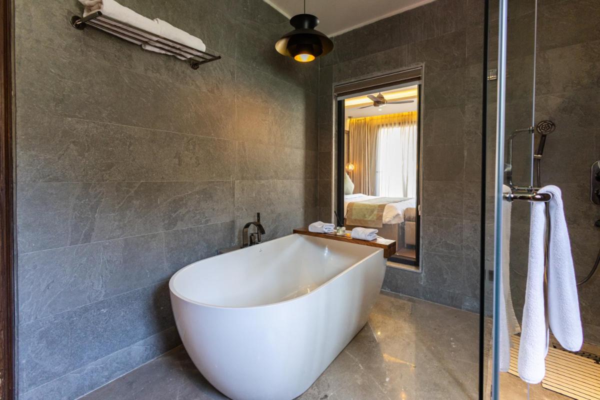 a white tub in a bathroom with a shower at Antalya By Divine Ganga Cottage in Rishīkesh