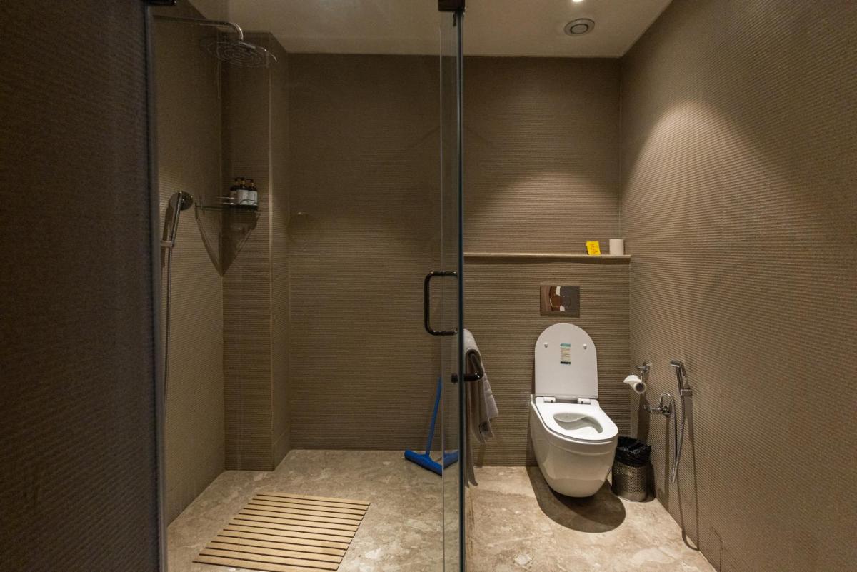 a bathroom with a toilet and a glass shower stall at Antalya By Divine Ganga Cottage in Rishīkesh