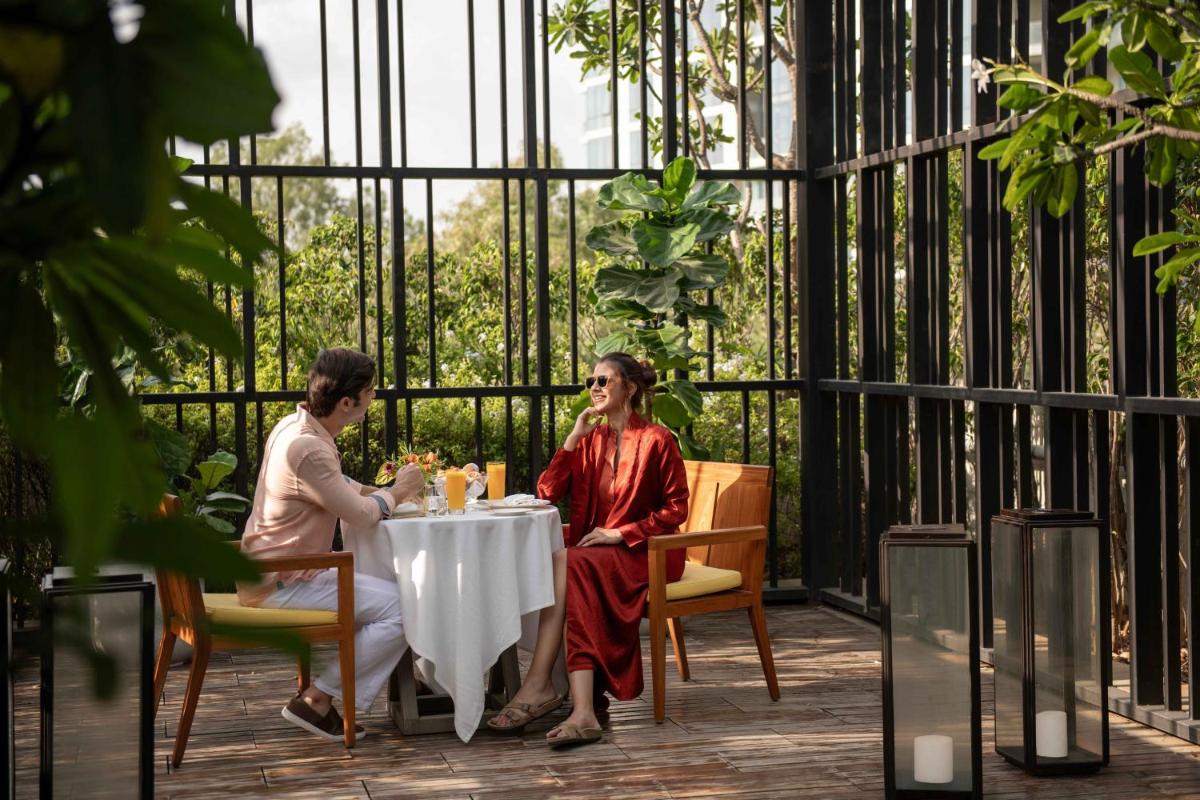 two women sitting at a table on a patio at Four Seasons Hotel Bengaluru at Embassy ONE in Bengaluru two women sitting at a table on a patio at Four Seasons Hotel Bengaluru at Embassy ONE in Bengaluru