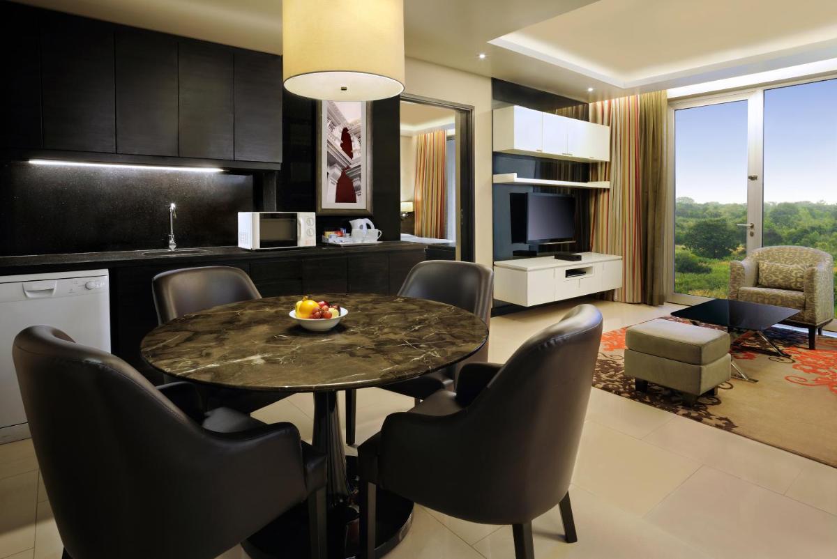 a kitchen and living room with a table and chairs at DoubleTree Suites by Hilton Bengaluru Outer Ring Road in Bengaluru