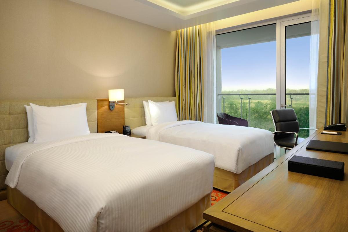 a hotel room with two beds and a window at DoubleTree Suites by Hilton Bengaluru Outer Ring Road in Bengaluru
