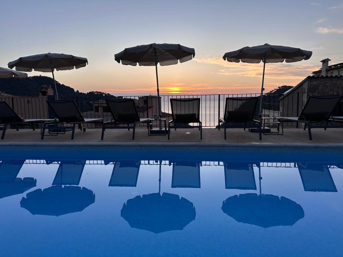 Un grupo de sillas y sombrillas junto a una piscina. en Maristel Hotel & Spa - Adults Only, en Estellencs
