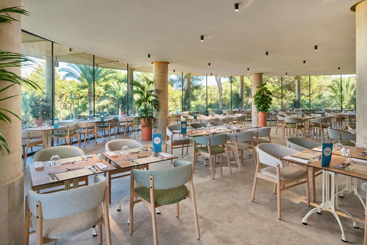 Un restaurante con mesas, sillas y ventanas. en Grupotel Cala Marsal Nature Hotel - New Reopening 2025, en Portocolom
