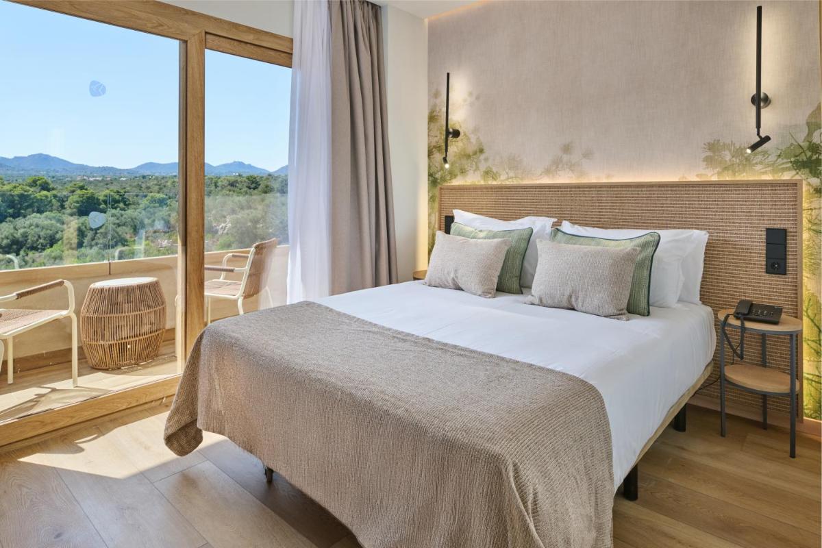 Un dormitorio con una cama grande y un balcón. en Grupotel Cala Marsal Nature Hotel - New Reopening 2025, en Portocolom