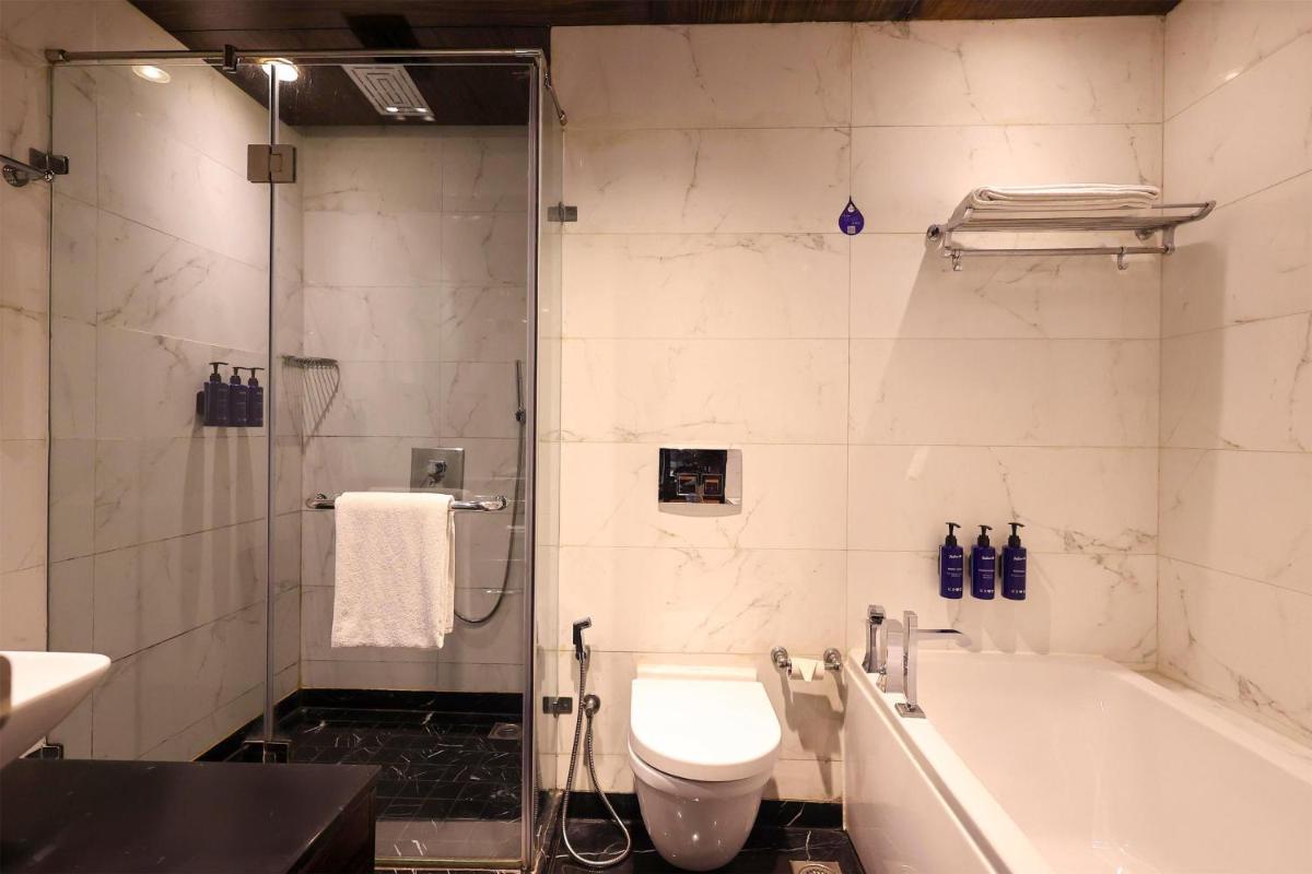 a bathroom with a tub and a toilet and a shower at Radisson Blu Hotel New Delhi Paschim Vihar in New Delhi a bathroom with a tub and a toilet and a shower at Radisson Blu Hotel New Delhi Paschim Vihar in New Delhi