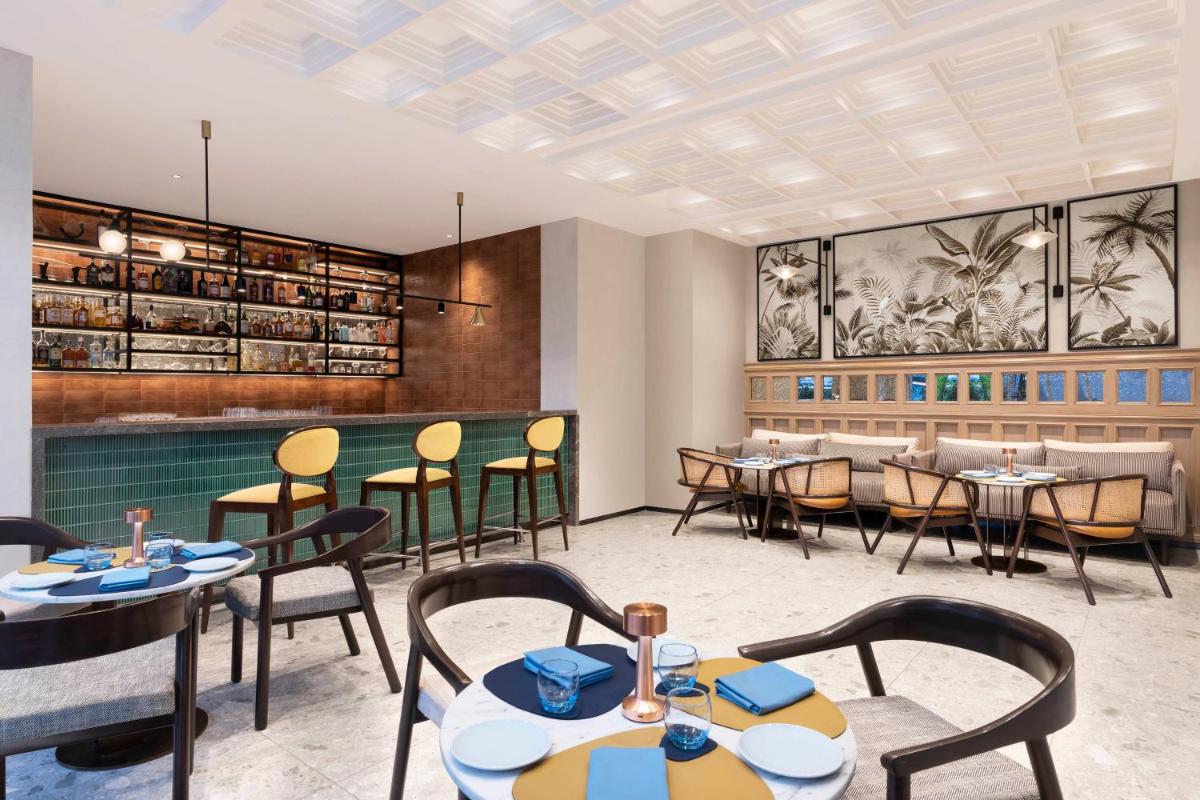 a restaurant with tables and chairs and a bar at Novotel Pune Viman Nagar Road in Pune
